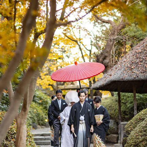 厳かな神前式後の「花嫁御寮」。 朱傘の下、親御様と一緒に一歩づつゲストの皆様のもとへ進みます。 紅葉で赤く彩る日本庭園で、この時期ならではの趣深い演出となりました。